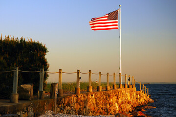 An American flag waves at the end of a jetty jutting out into the sea from an estate on the Fourth of July