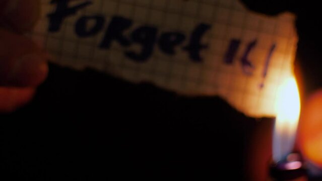 Symbolic burning of pieces of paper with the word "FORGET IT"