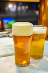 Fresh draught lager or IPA beer is glass served in indoor cafe close up, pint of beer