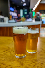 Fresh draught lager or IPA beer is glass served in indoor cafe close up, pint of beer