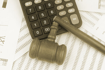 Broken wooden judge gavel and calculator on financial data.