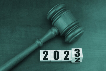 Judge gavel and numbers 2022 with 2023 on wooden cubes. Concept of new laws in year 2023.
