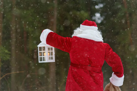Santa Claus with bag of Christmas gifts is walking through snowy forest. Animator or parent in Santa Claus costume is rushing to a holiday for children. St. Nicholas Day.