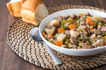 A bowl of fresh homemade beef stew served with dinner buns.