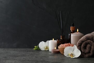 Beautiful composition with burning candles and different spa products on dark grey table. Space for...