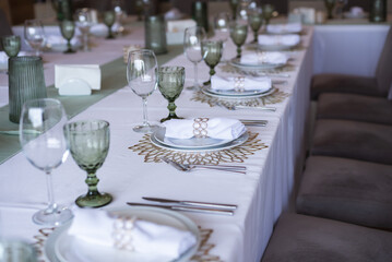 
Serving and decoration of the wedding table. Glasses, spoons, forks and white napkins