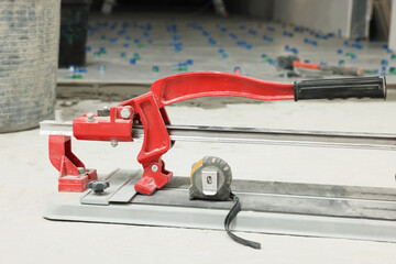 Tile cutter and tools on floor indoors, closeup