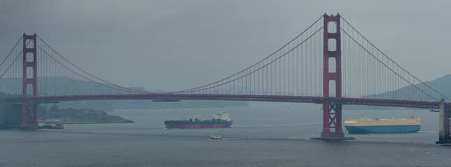 Cargo ships on the move heading out to sea under the Golden Gate Bridge ca