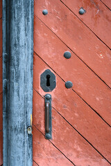 Weathered red wood door with old iron lock and handle
