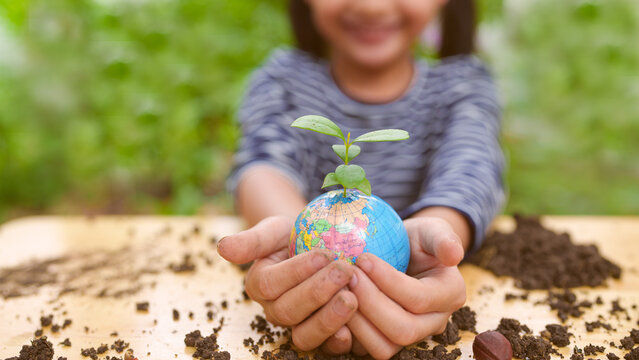 Banner of blurred  little girl is holding plant and globe model together, concept of ESG, environment, earth day, sustainability, world environment day, montessori education for kid and home school.