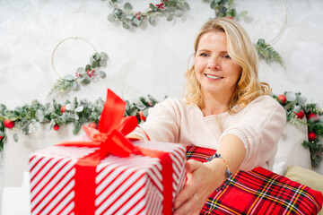 Obraz na płótnie Canvas Christmas, new year, holidays concept. Happy Woman getting gift box as christmas present. Surprise For You. Excited woman getting unexpected xmas decorated gift box.