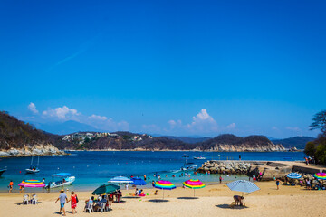 holidays in mexican beach with tourist walking in the sand, huatulco oaxaca 