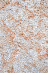 Closeup of hand-hewn stone wall, light colored stone in yellows, oranges, and browns
