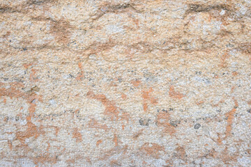 Closeup of hand-hewn stone wall, light colored stone in yellows, oranges, and browns
