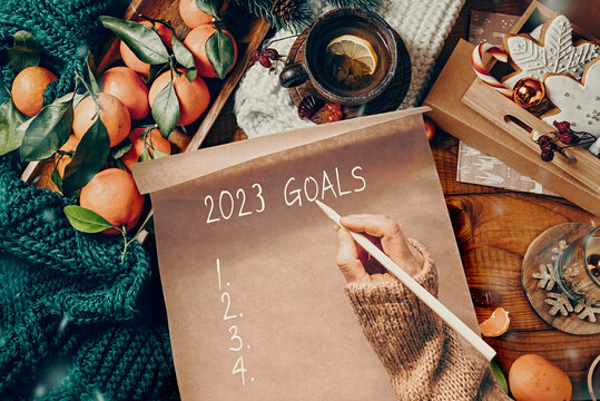 Women's hands write goals for the year on a decorated Christmas table