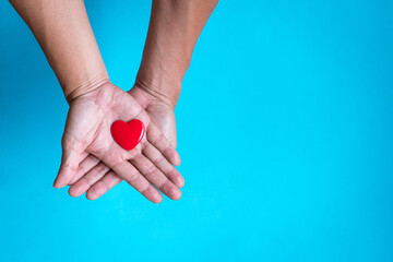 Heart health concept. Red heart shape on the palm of hand. Top view, copy space.