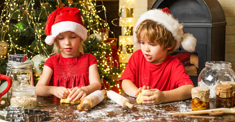 Cute little boy and girl twins preparing Christmas cookies in the home kitchen. Funny children are preparing gingerbread for Christmas.