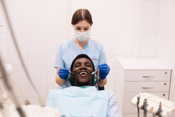 Professional female dentist examining man's teeth.