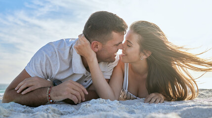 Love, kiss and couple at the beach for a date, vacation or relax with smile on the sand in summer. Freedom, travel and man and woman with affection, care and peace on a holiday by the sea together