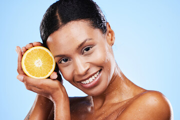 Skincare, beauty and orange fruit for black woman in studio for cosmetics, vitamin c and dermatology benefits with water drops on skin. Portrait, face and smile of model with natural product for skin