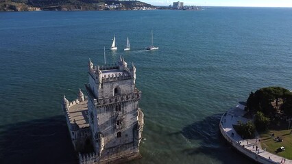 Aerial slow movement around Belem tower surrounded by water in Lisbon
