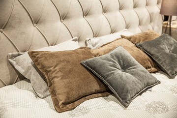 Headboard of a comfortable bed with pillows in beige tones. Close-up. Modern interior design.