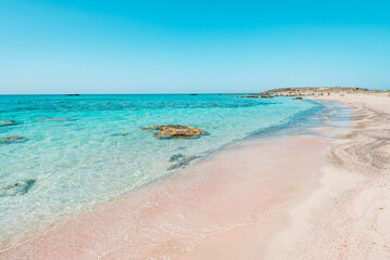 Elafonisi, crete island, greece: pink colored sandy beach with black rocks at the famous cretan lagoon - obrazy, fototapety, plakaty