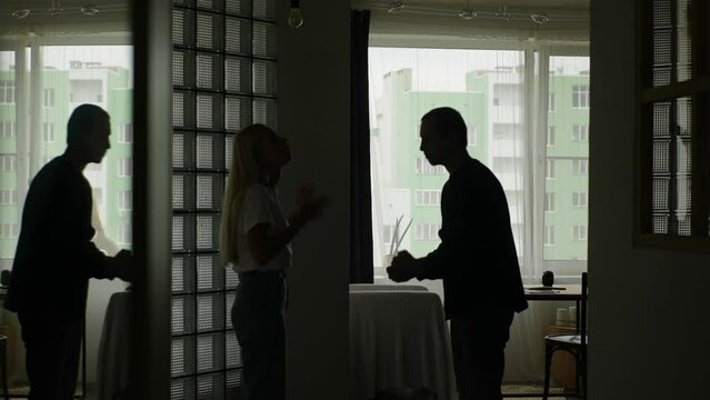 Silhouette of unrecognizable couple quarreling and fighting in evening at home, shouting at each other, gesturing, angry husband screaming at wife on background of window. Tracking shot in slow motion