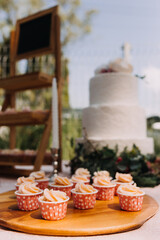 Gourmet cupcakes with white buttercream frosting and sprinkles on wooden background