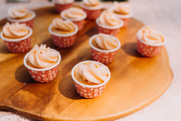 Gourmet cupcakes with white buttercream frosting and sprinkles on wooden background