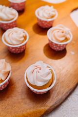 Gourmet cupcakes with white buttercream frosting and sprinkles on wooden background