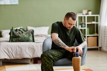 Portrait of military veteran fixing prosthetic leg and wearing army uniform, copy space