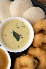 South Indian breakfast-Idli, sambar, wada, coconut chutney. Served in plate wooden background