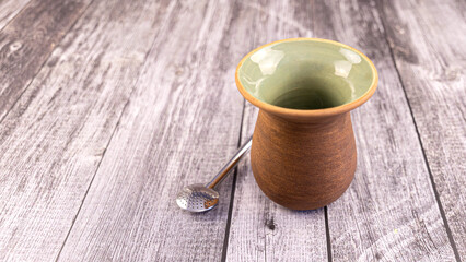 Clay mate calabash with bombilla on grey wood background