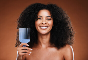 Black woman, hair care and smile in portrait with comb, afro pick or beauty against brown backdrop....
