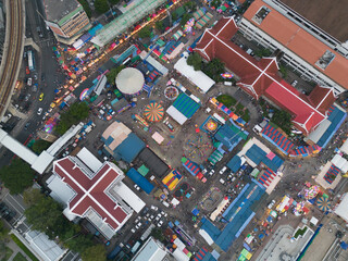 Aerial top view of amusement park in night temple fair, and night local markets. People walking...