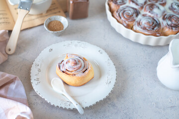 Homemade cinnamon rolls in glaze on a white plate, stone background, Copy space