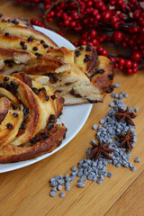 Chocolate and orange jam braided Brioche bread with one slice on a plate on wooden table with Christmas decoration