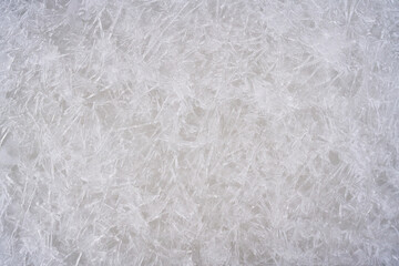 Fresh ice surface texture. Winter background with frozen snowflakes and snow mounds.