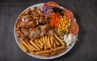 Doner kebab or gyros on a plate with french fries and salad.