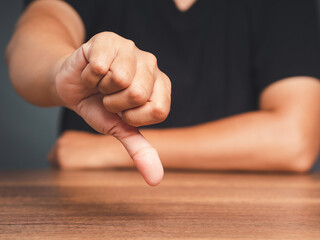 Close-up of young man's hand showing a thumbs down for dislike service