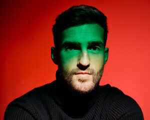 Fashion, face and trendy man in studio with red background, green light and cool style, elegant and...