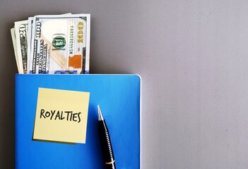 Cash money in dollars and a pen on a blue notebook, isolated on grey background, concept of legally...