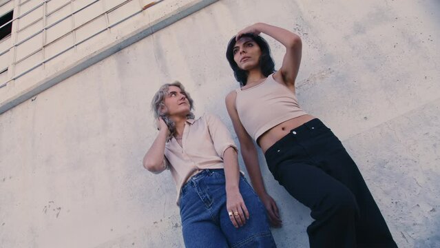 models standing and posing outdoors by wall