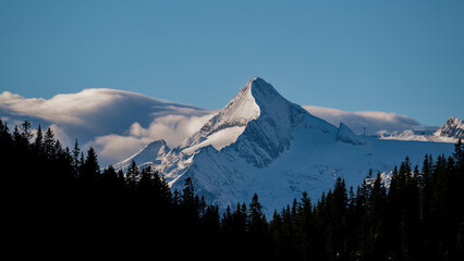 beautiful view to the snowy kitzsteinhorn in austria at a sunny atumn day with foehn clouds in the...