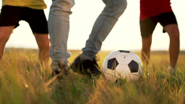 Happy family concept.Active outdoor lifestyle.Child with dad play soccer with ball on lawn.Family on green grass in field.Group of people in sun. Dad and son and daughter play with ball on green grass