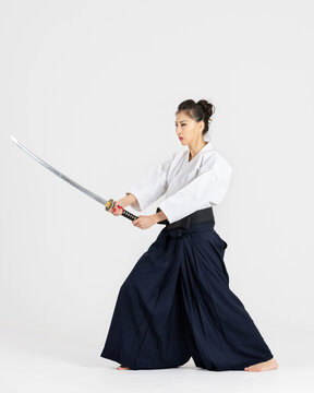 Aikido master woman in traditional samurai hakama kimono with black belt with sword, katana on white background. Healthy lifestyle and sports concept.