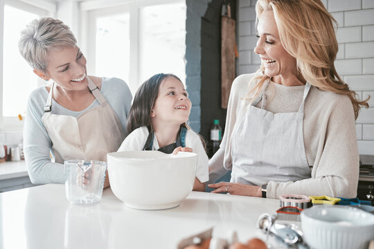 .Child, grandmother and mom teaching cooking together in kitchen bonding, quality time or fun activity at home. Happy mother, grandma and excited kid chef learning to bake cake with family support.