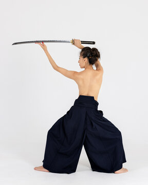 Aikido master woman in traditional samurai hakama kimono with black belt with sword, katana on white background. Healthy lifestyle and sports concept.
