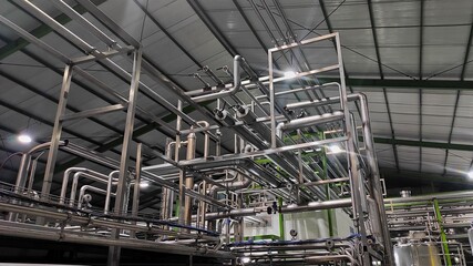 Stainless steel pipes in production room of factory to flow water and milk
